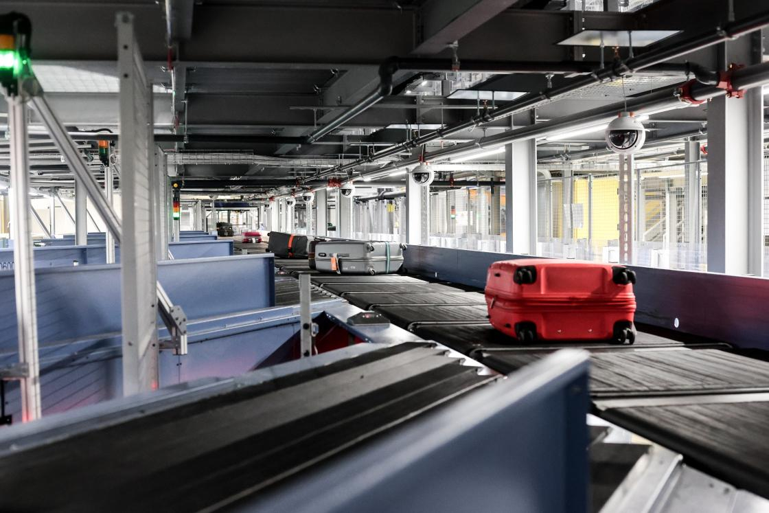 Bagagli in movimento sulla rampa di trasferimento, sistema di consegna aeroportuale, bagagli in viaggio verso volo, tecnologia di gestione bagagli, trasporto bagagli sicuro, logistics aeroportuale.