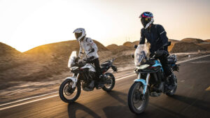 Moto Morbidelli T352X adventure in desert, due motociclisti con casco, paesaggio arido, tramonto, vie panoramiche, veicolo sostenibile, viaggio all'aperto.